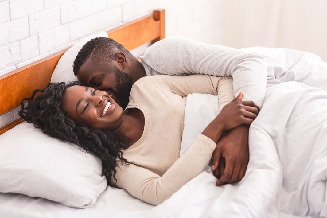 Couple in a comfy bed at home snuggling.